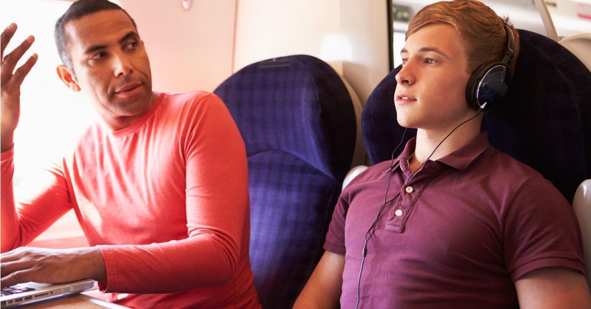 young man disturbing train passengers with loud music picture id