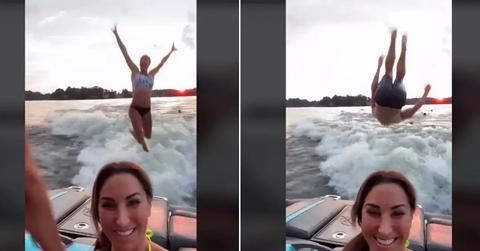 Two people jumping off the back of a moving boat.
