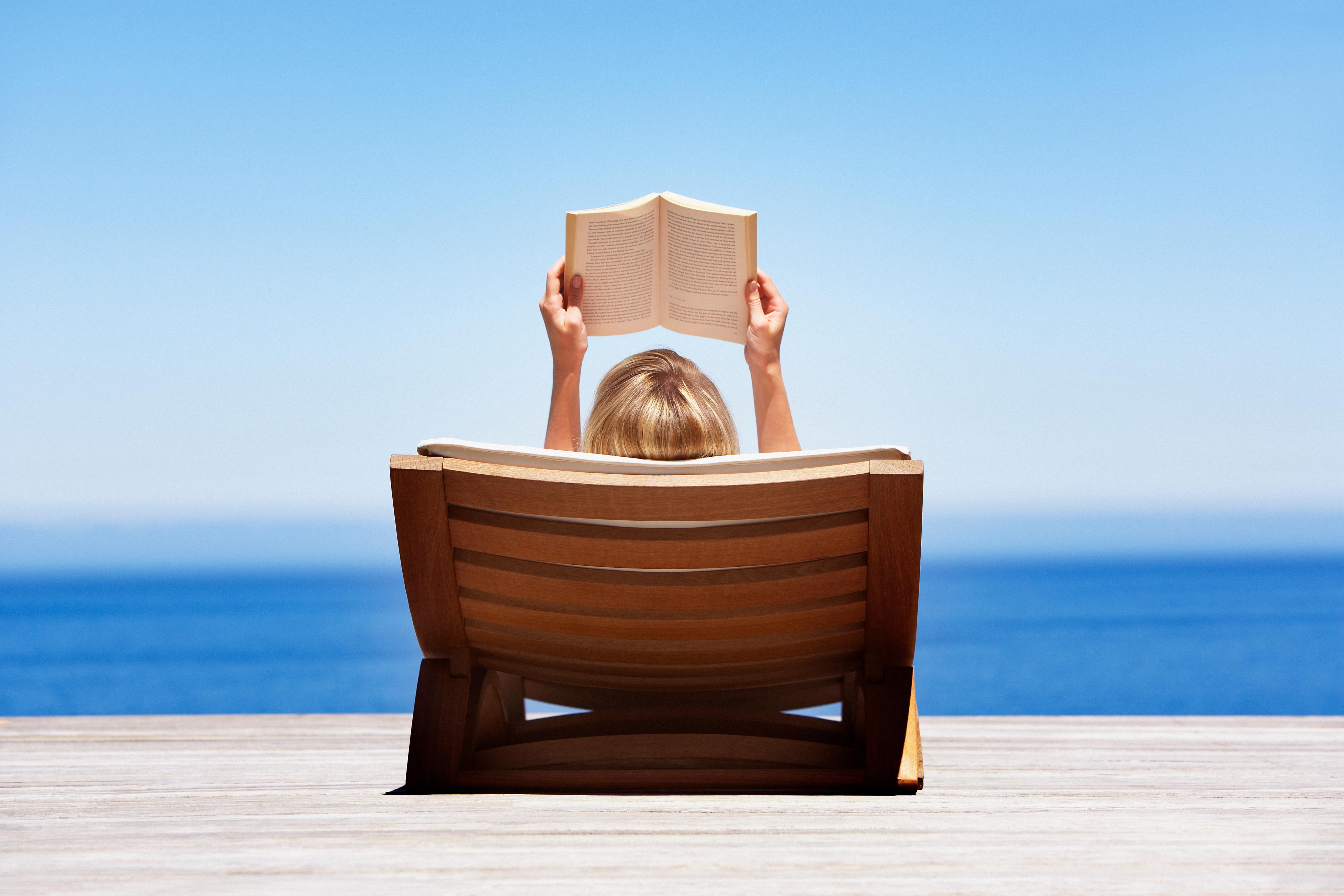 Girl reading a book by the beach