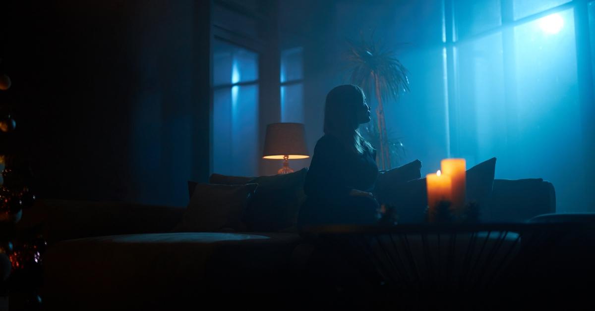 woman on couch in dark with blue light outside