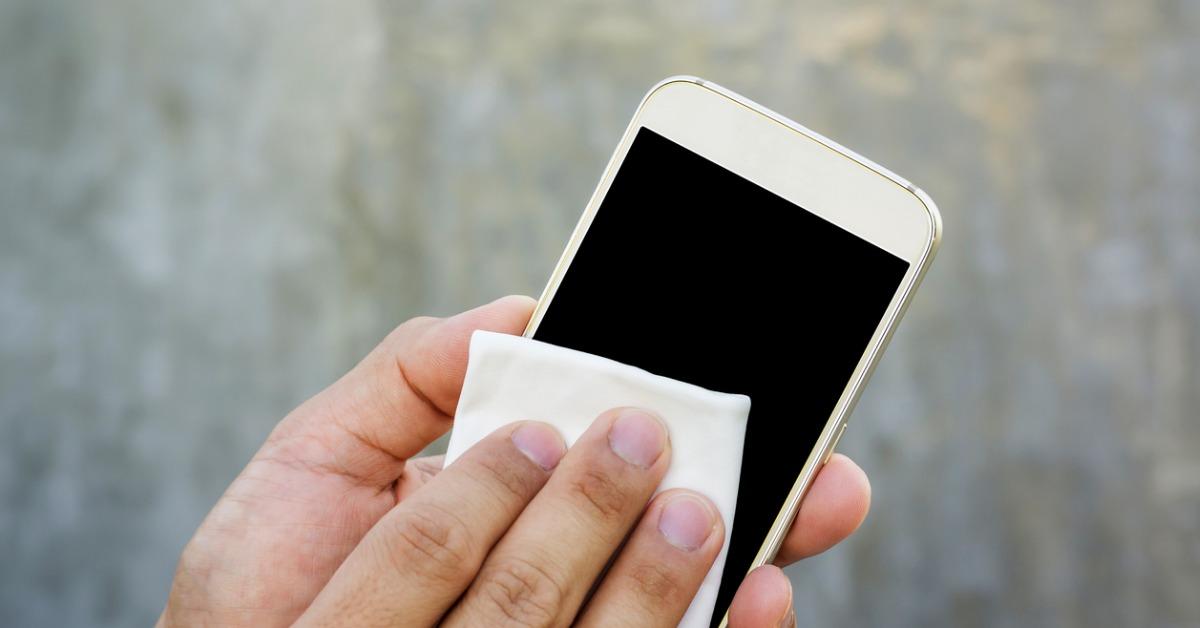 man cleaning his smartphone with a microfiber cloth picture id