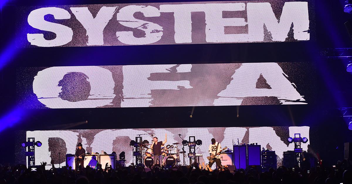 System of a Down performing on stage with their name behind them.