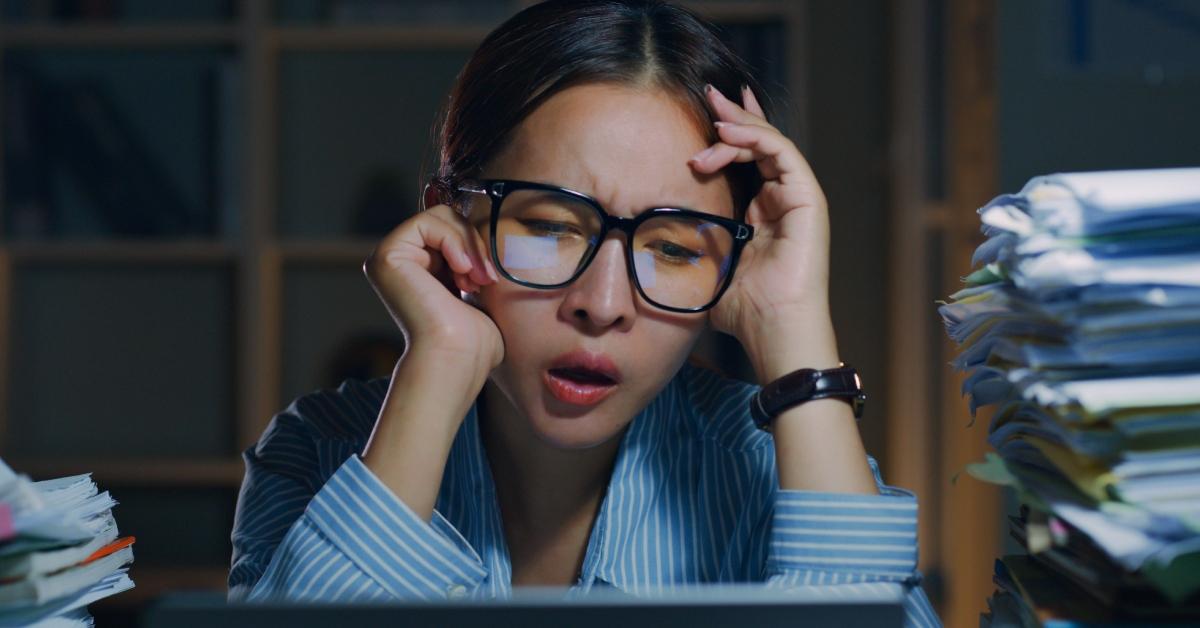 female office employee feeling bored, unhappy and burnout while working overtime at night in office