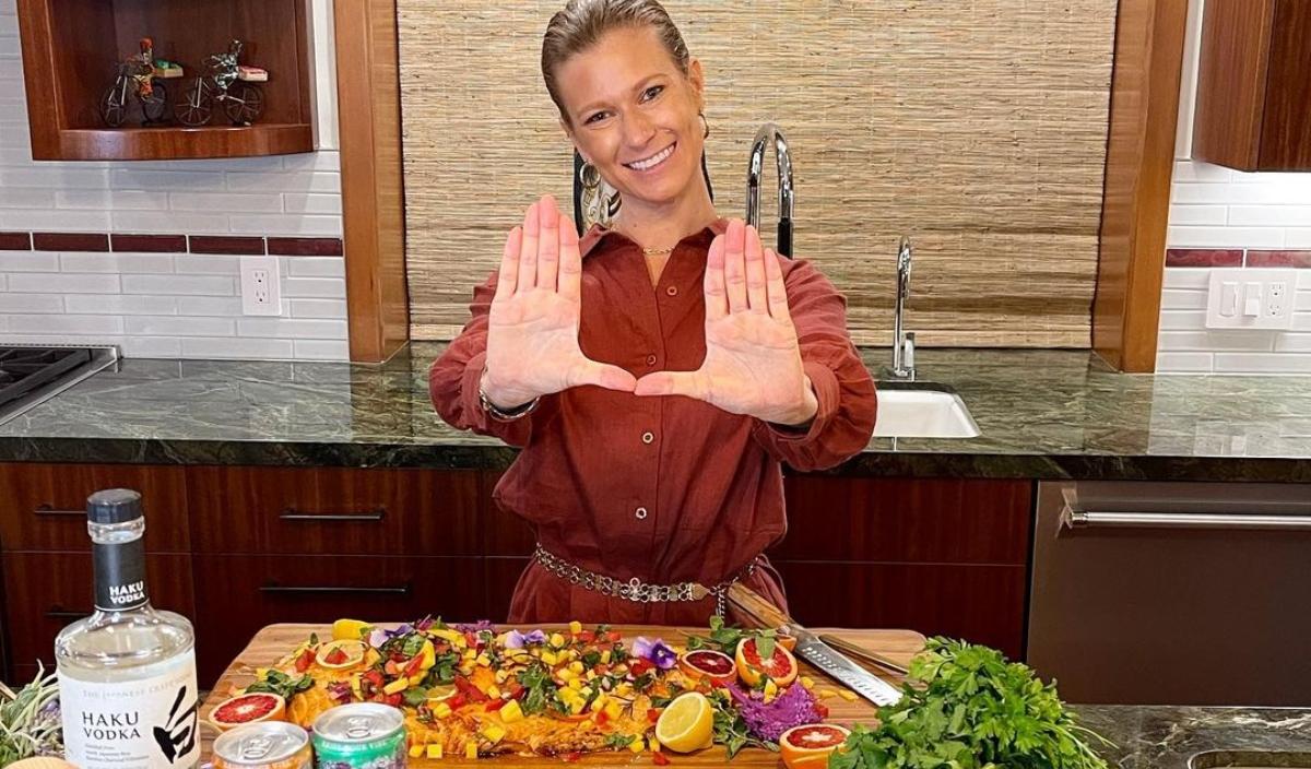 Lisa Weintraub stands at a kitchen island with a cutting board in front of her