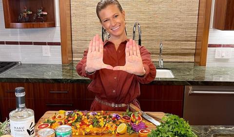 Lisa Weintraub stands at a kitchen island with a cutting board in front of her