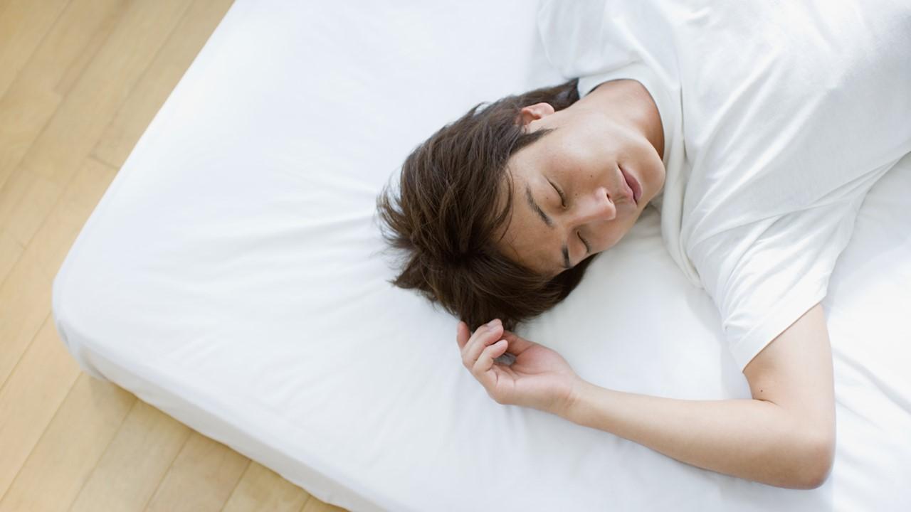 A person sleeping on a mattress on the floor