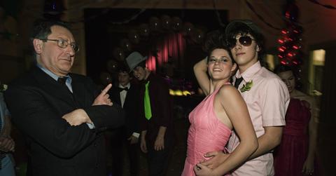 A couple dancing at prom with a teacher watching