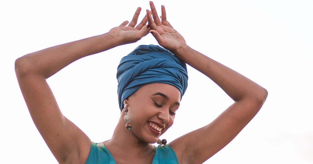 A woman holds her arms over her head while smiling.