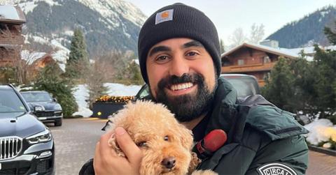 George Janko holding a dog near a mountain.
