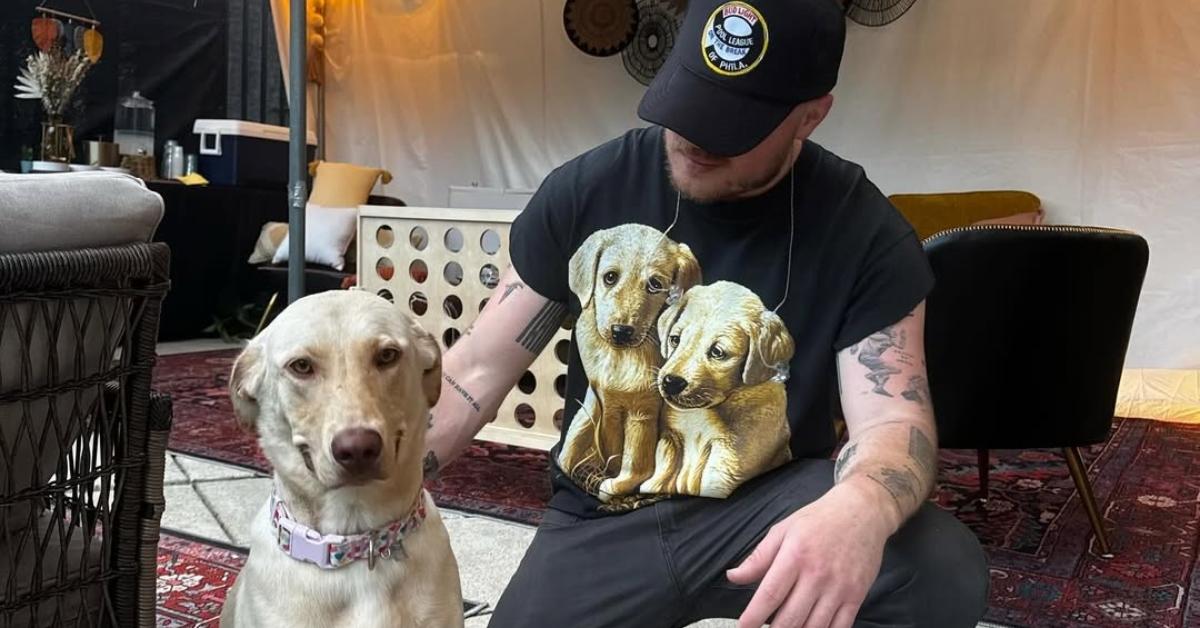 Zach Bryan with his dog in a tent outside.