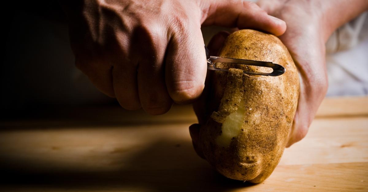 Close-up of cook peeling raw potato