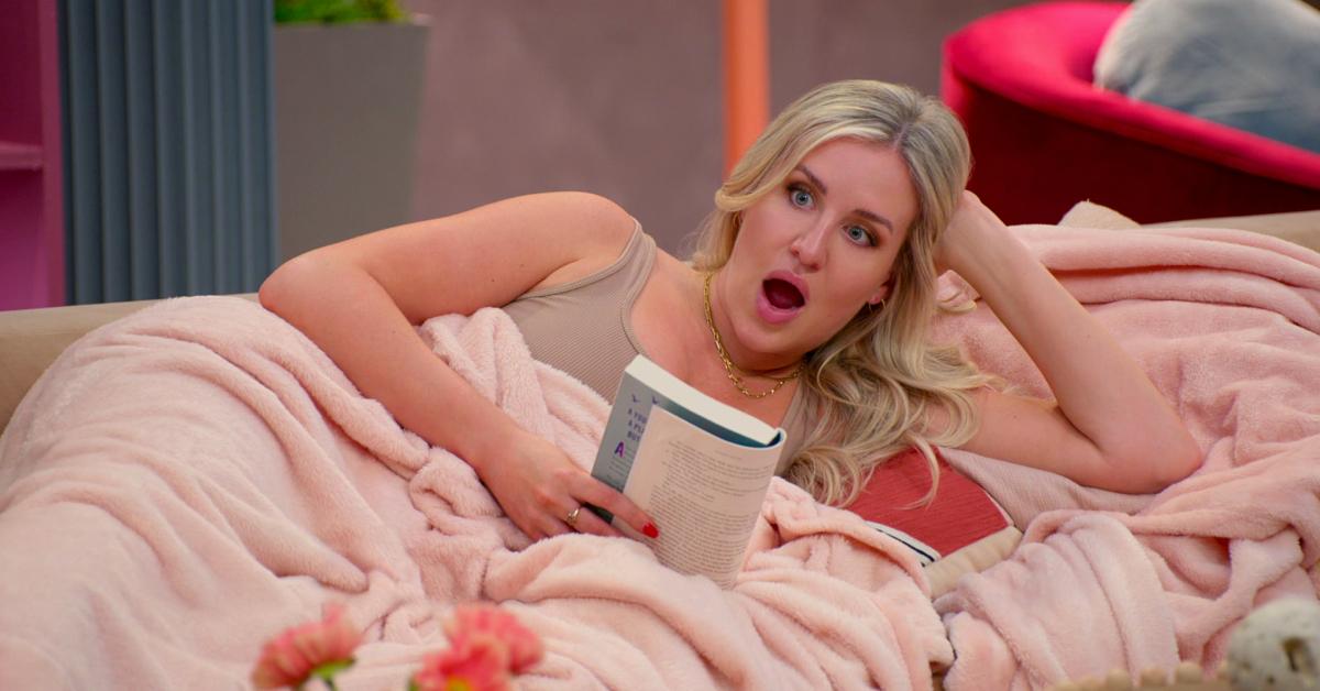 Laura Dadisman wears a shocked expression on her face as she reads a book under a pink blanket.