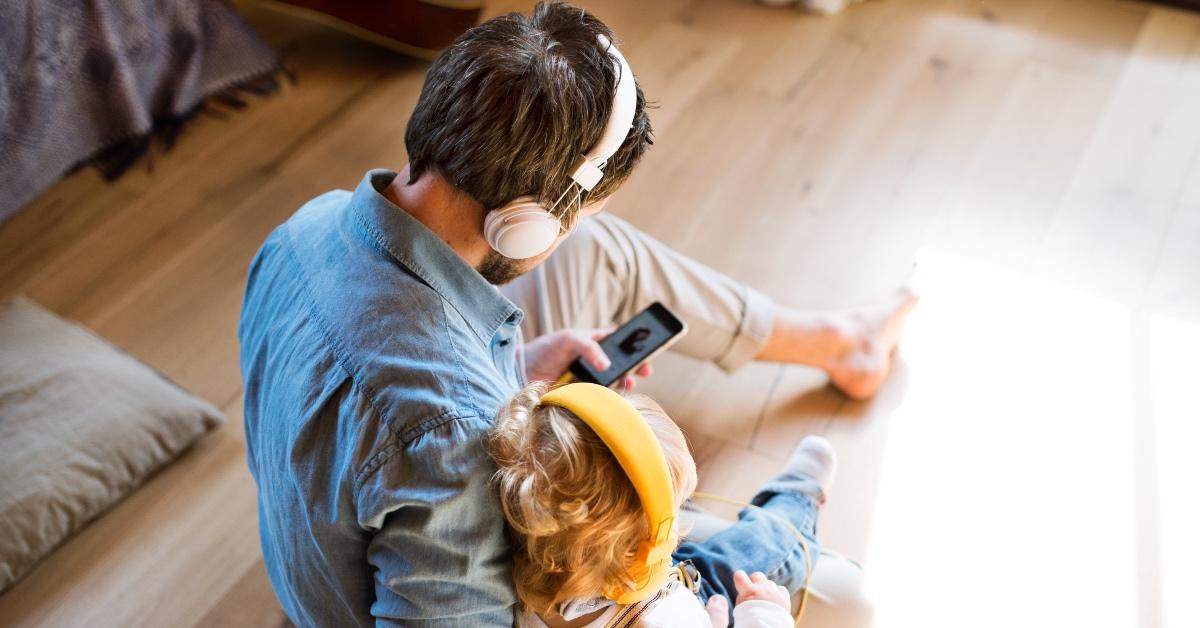 A father and daughter wear headphones together.