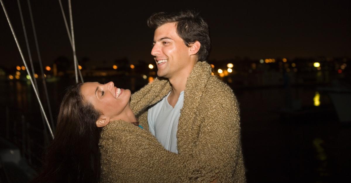 Laughing couple wrapped in a blanket