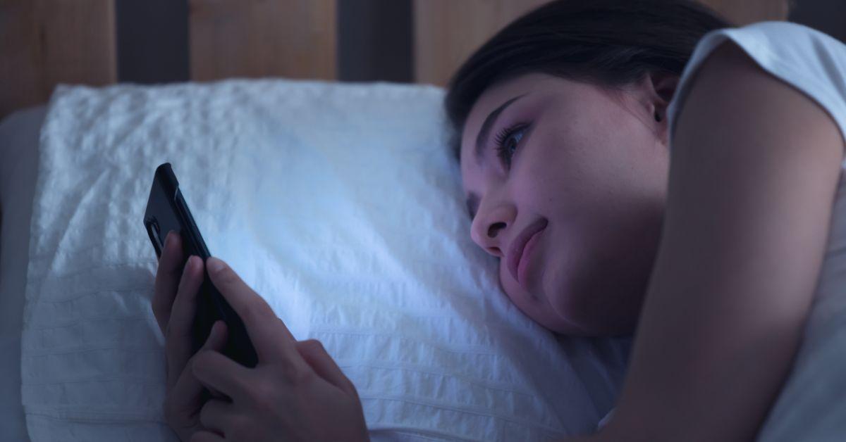 woman in bed staring at phone