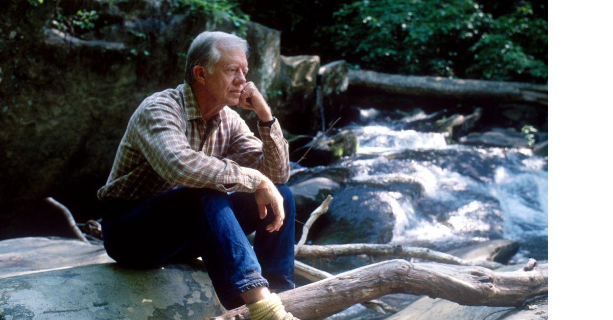 Jimmy Carter sitting on a rock near a creek in 1988. 