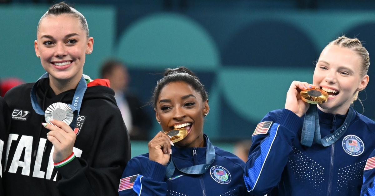 Simone Biles biting her Olympic gold medal.