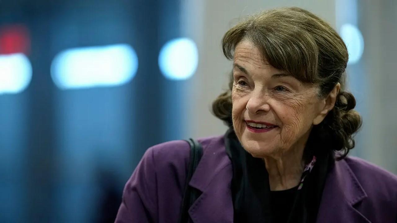 Dianne Feinstein smiling and wearing a purple jacket