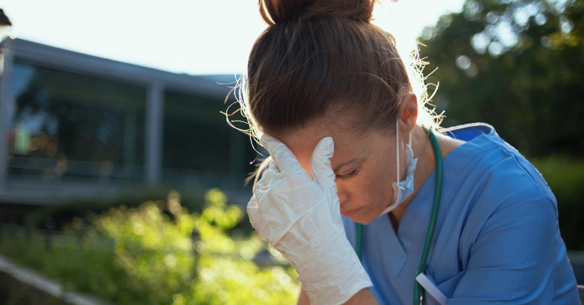 A stressed medical worker sits outside the hospital.