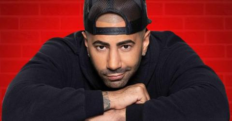 Fousey posing in front of a red background.
