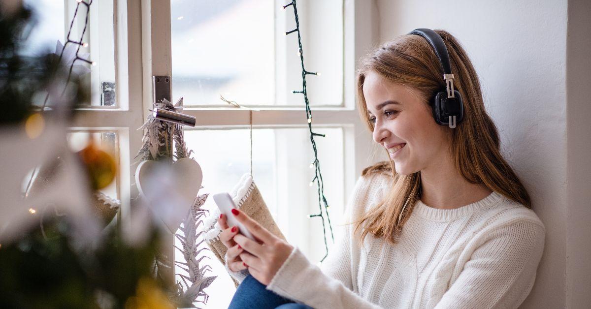 Girl wearing headphones, listening to music around holiday decorations
