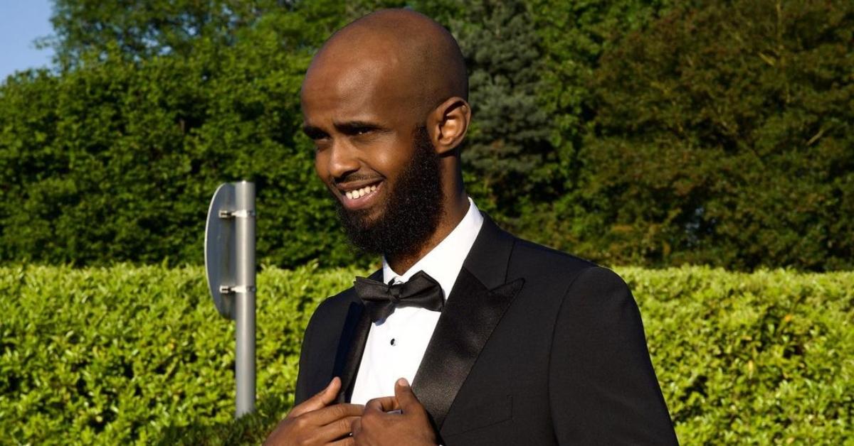 Darkest Man squints and looks away from the camera wearing a suit and tie.