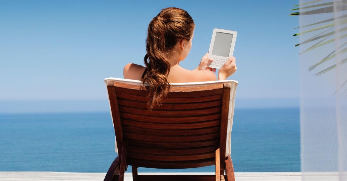 Woman reading using an e-reader on vacation. 