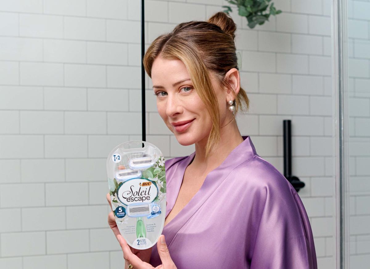 Lo Bosworth holds BIC Soleil razors as she stands in the bathroom wearing a purple.