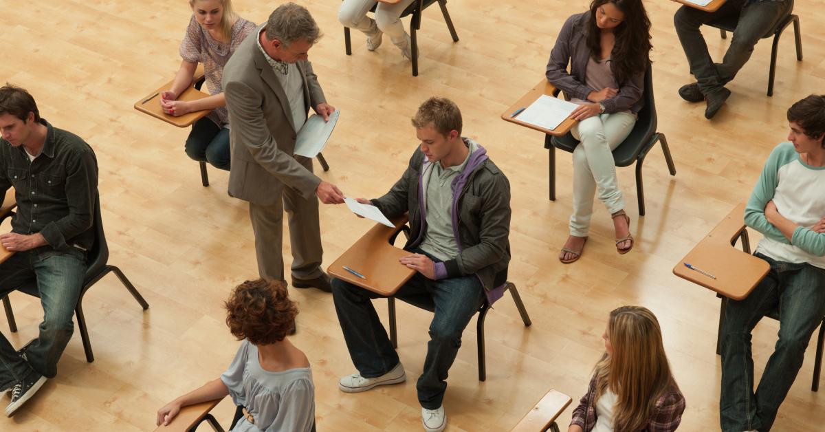 A teacher hands out the test to his students.