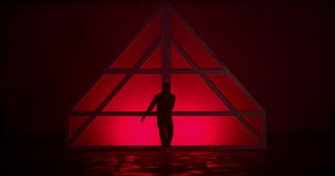 A dancer in front of red lights