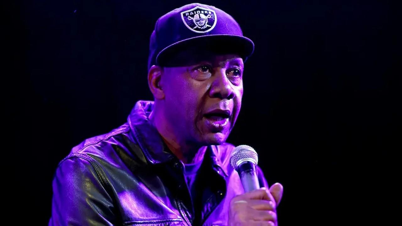 Mark Curry on stage wearing a Raiders hat