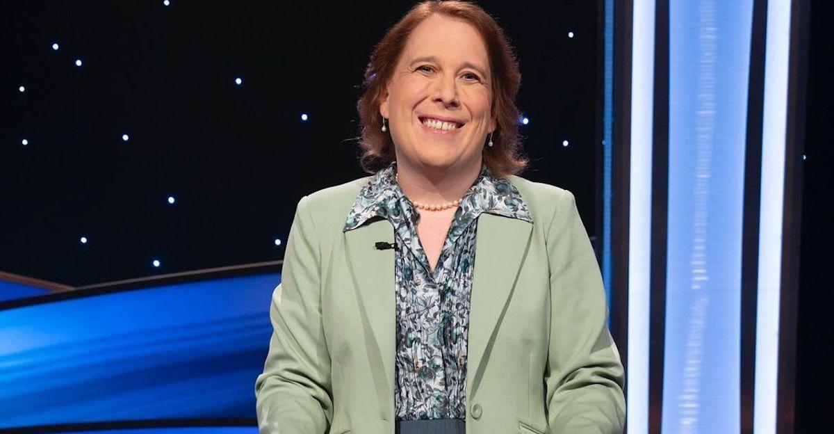 Amy Schneider wears a green blazer on the 'Jeopardy!' set and smiles