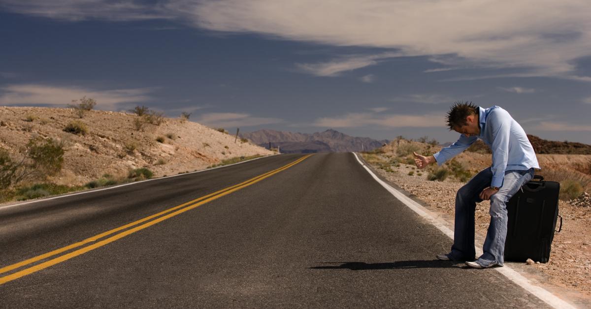 A man stranded on the side of the highway.