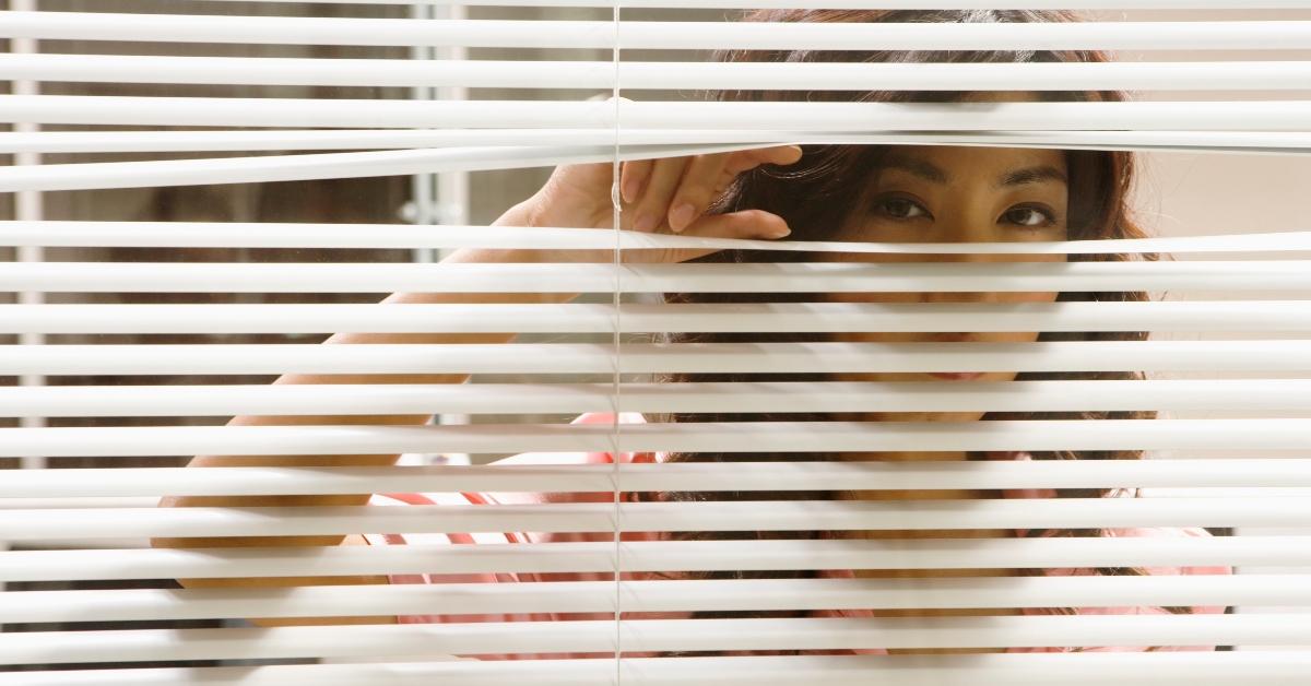 A woman peeking through her blinds.