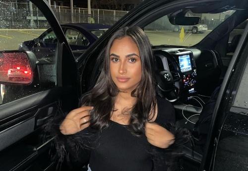 Morgan Bailey posing in front of car for Instagram post.