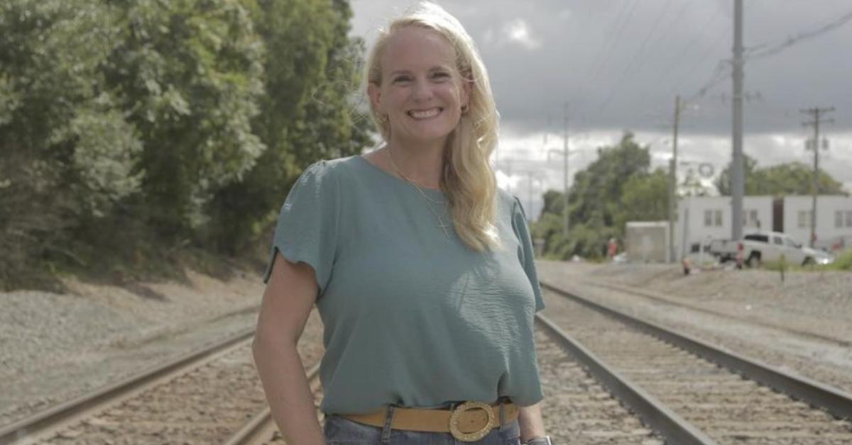 Holly Dunn Pendleton smiling by a set of train tracks