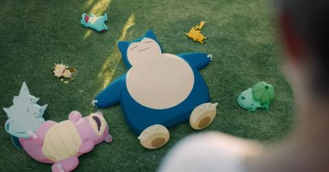 Snorlax sleeping in a grassy field next to other Pokémon.