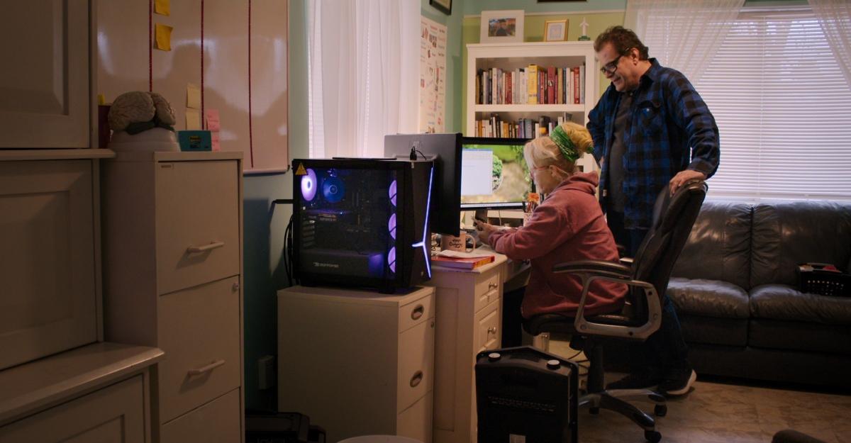 Christine and Tolga look at a computer during the documentary Trust Me: The False Prophet.