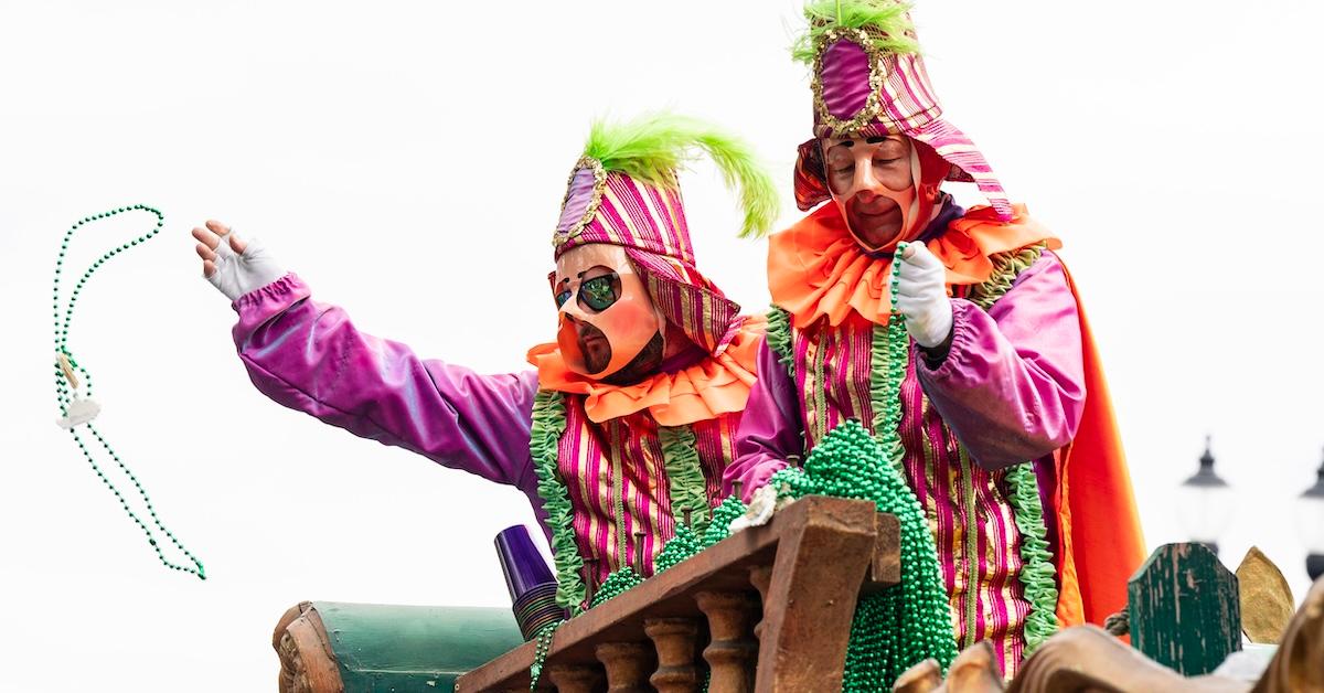 Two men dressed as jesters throw beads at Mardi Gras 2024