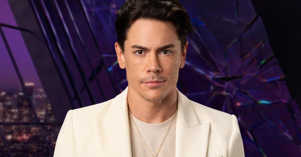 Tom Sandoval in a white suit in front of a purple wall