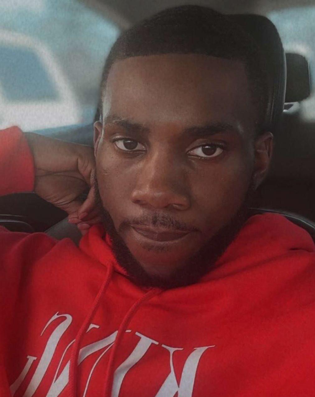 Trey Reed sitting in the car with a red sweatshirt.