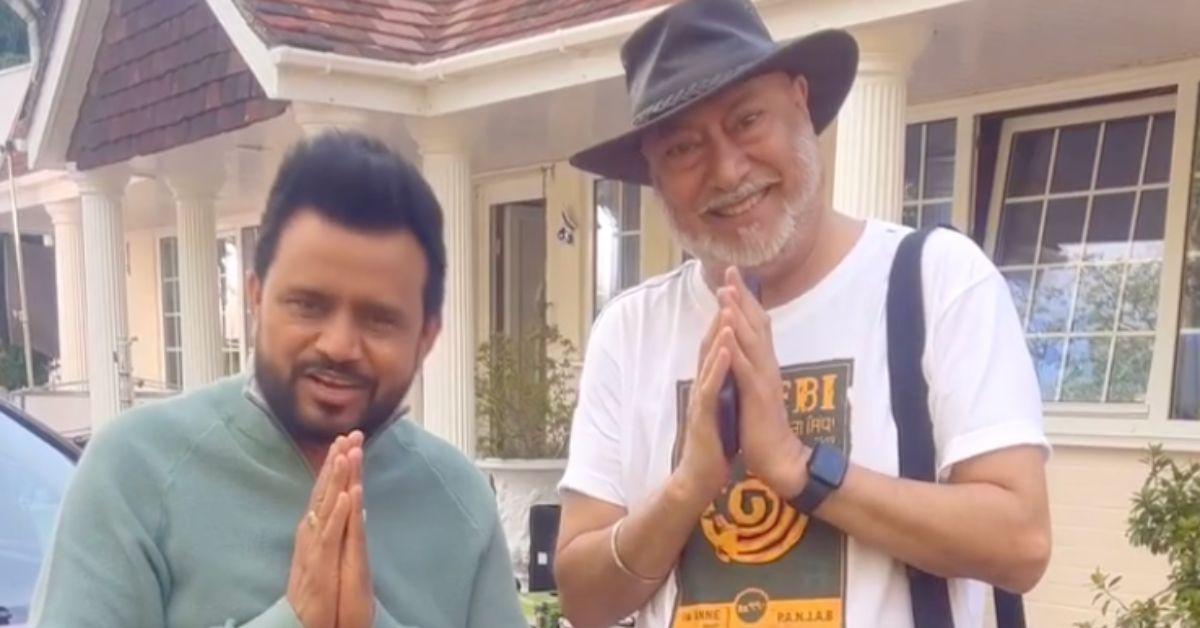 Jaswinder Bhalla holding up prayer hands with another man. 