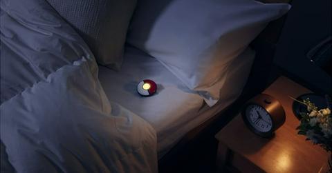 The Pokémon GO Plus+ sleep tracker resting on a mattress.