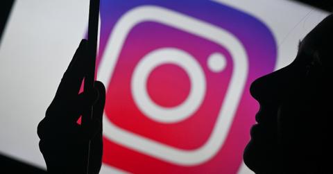 Woman looking at phone with Instagram logo behind her