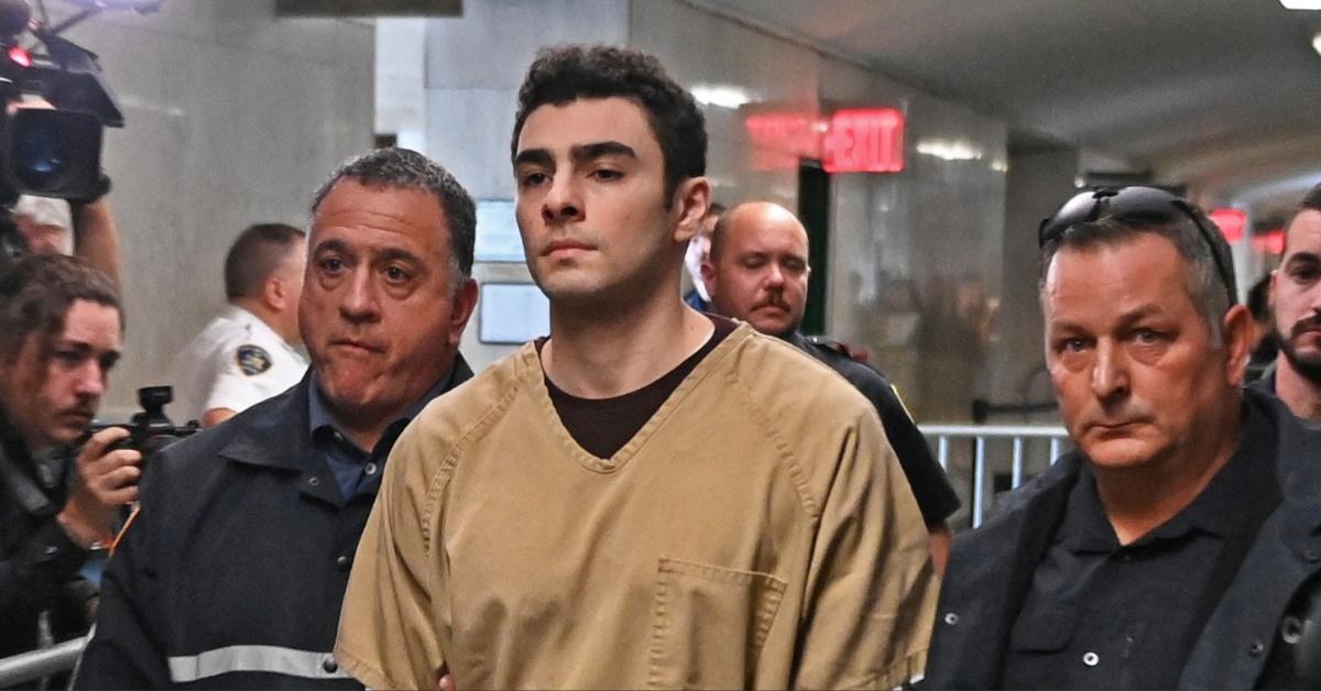 Luigi Mangione is escorted through a building by the authorities.