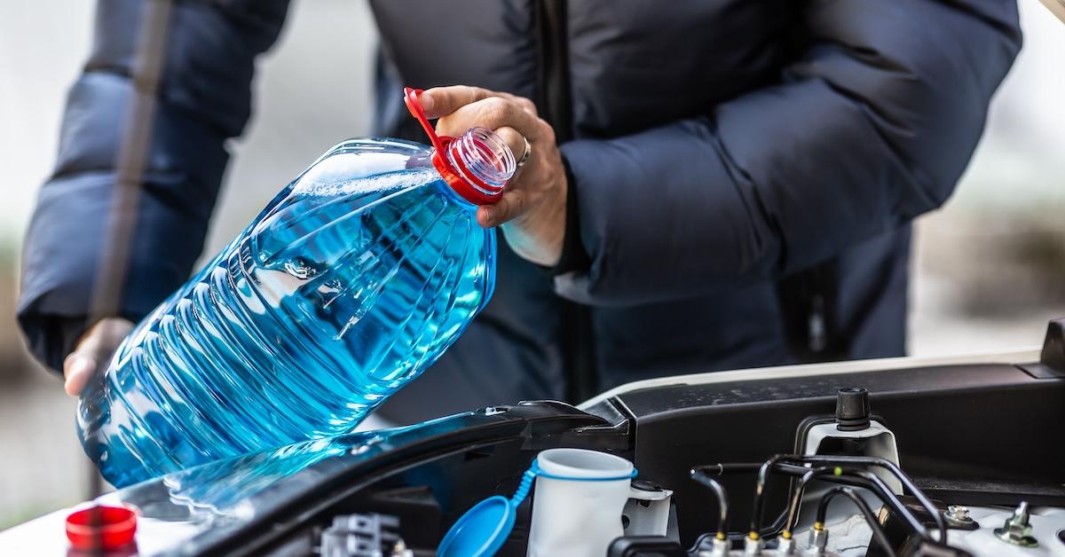 A person fixing to pour blue antifreeze into their vehicle