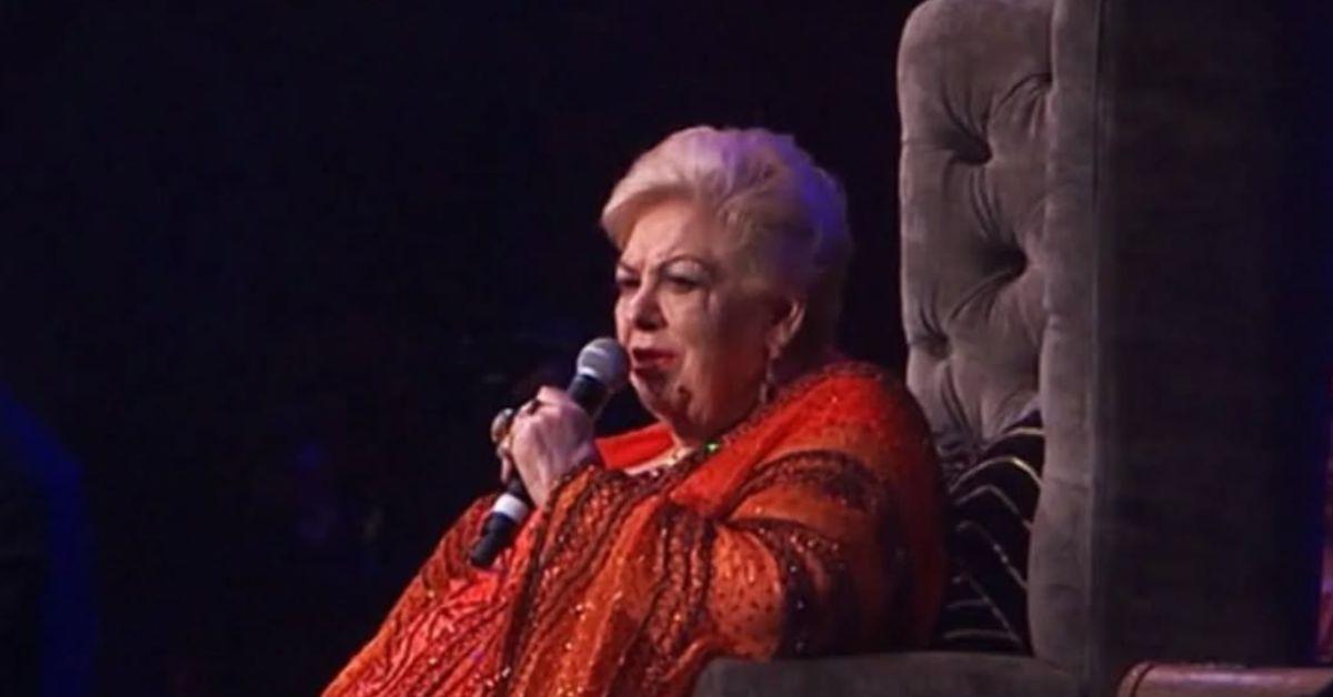 Paquita La del Barrio sitting in a chair talking into a microphone. 