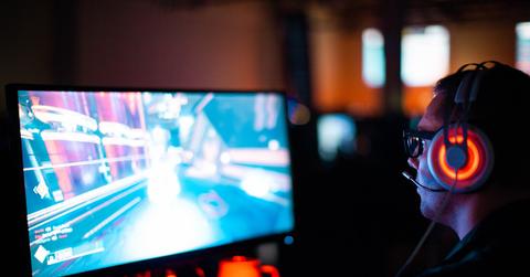 Gamer with red headphones planning a shooting game on a PC screen.