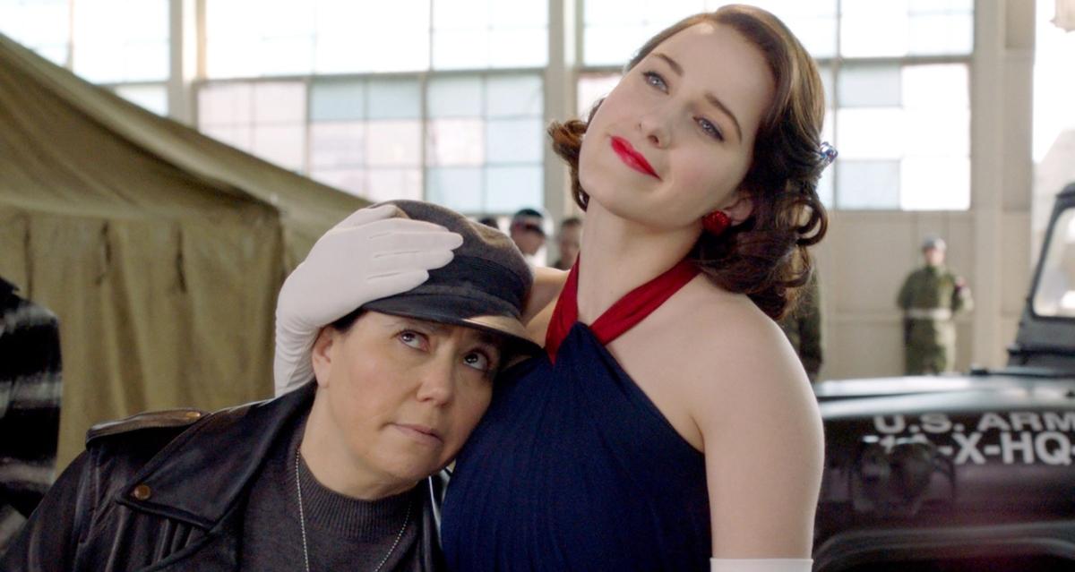 Midge holds Susie against her in front of Army trucks on 'The Marvelous Mrs. Maisel'