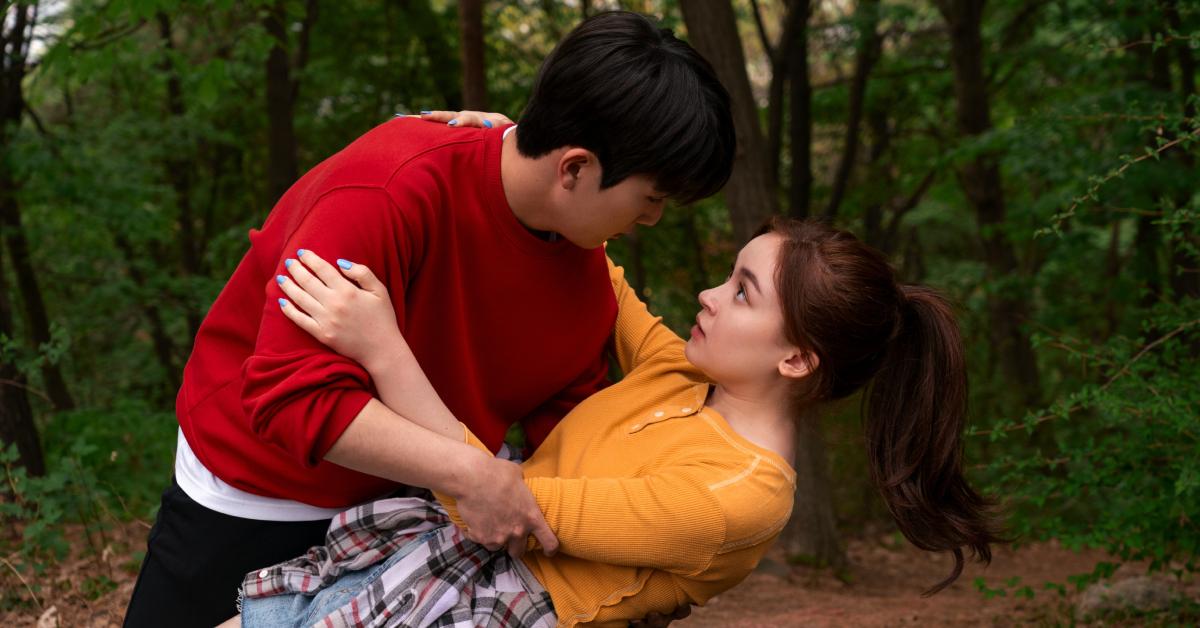 Dae (Minyeong Choi) catches Kitty (Anna Cathcart) in the middle of the woods.